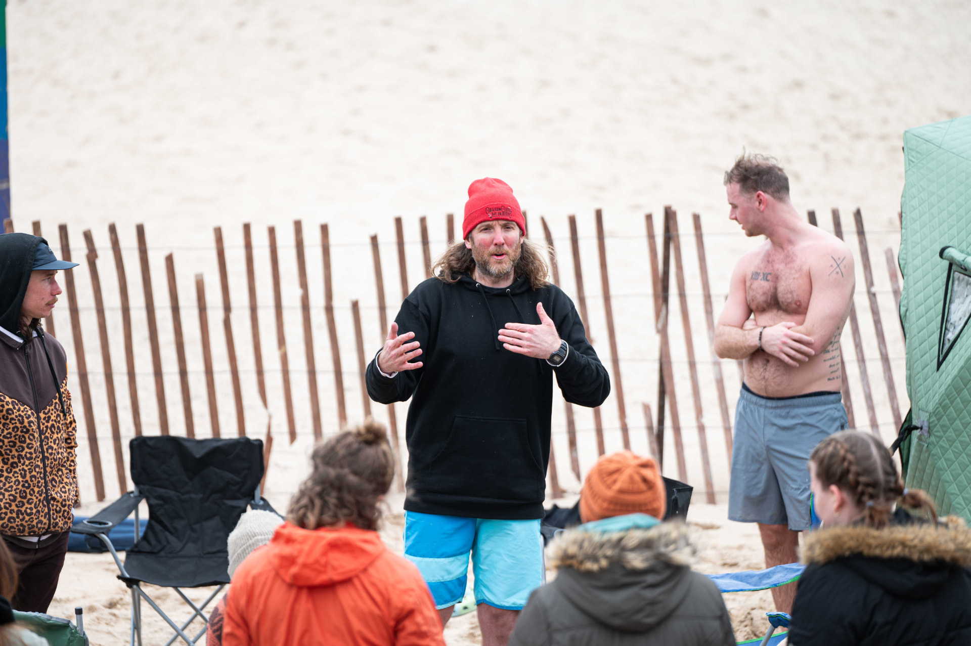 A Hive leader speaking to a group gathered on the Lake Michigan beach beside a sauna tent